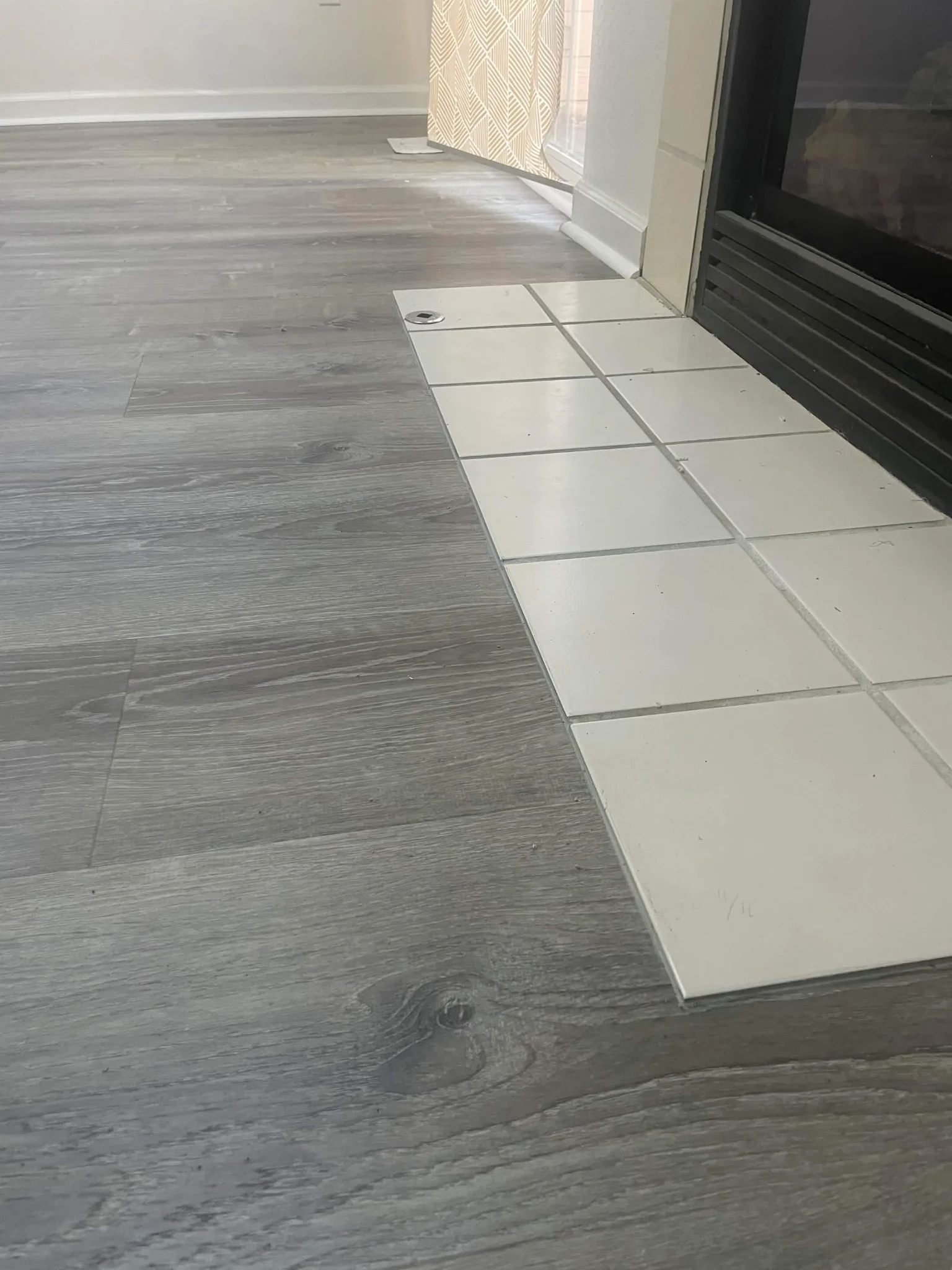 Transition strip between wood-look flooring and white tile with dark grout